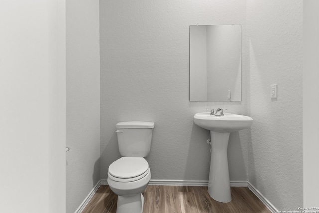 bathroom with hardwood / wood-style flooring, toilet, and sink