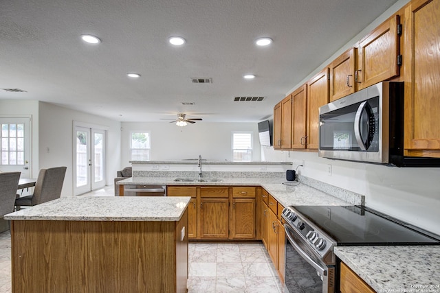 kitchen featuring a center island, french doors, sink, ceiling fan, and stainless steel appliances