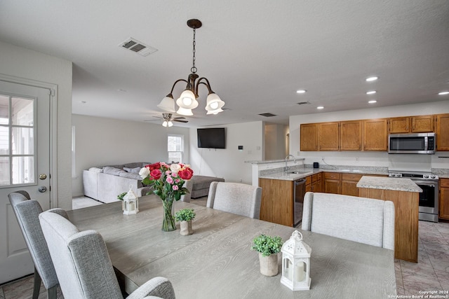 dining space featuring ceiling fan with notable chandelier and sink