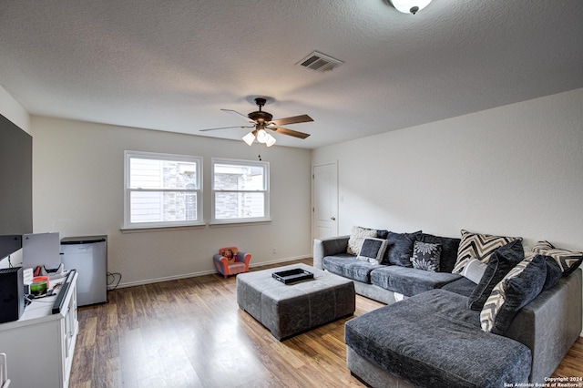 living room with ceiling fan, wood-type flooring, and a textured ceiling