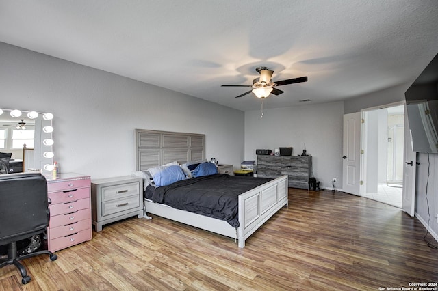 bedroom featuring ceiling fan, a textured ceiling, and light wood-type flooring