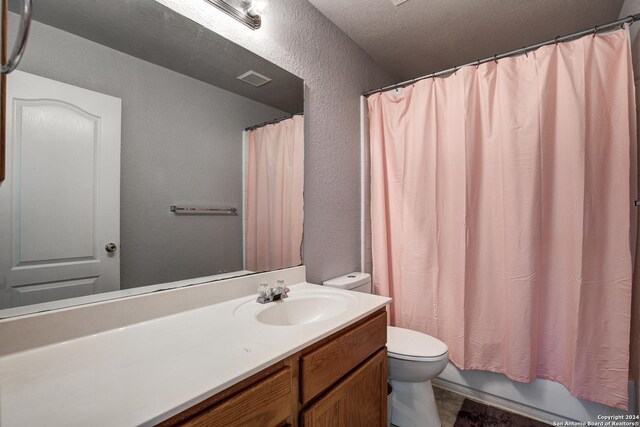 full bathroom with vanity, toilet, shower / bath combo with shower curtain, and a textured ceiling