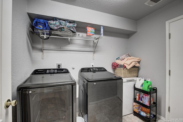 washroom featuring washing machine and clothes dryer and a textured ceiling