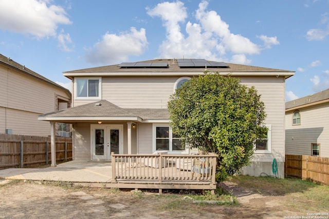 back of property with french doors, solar panels, and a wooden deck