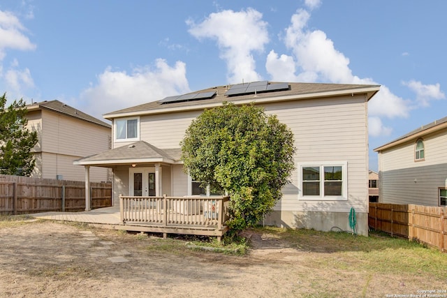 rear view of property featuring solar panels, a wooden deck, and french doors