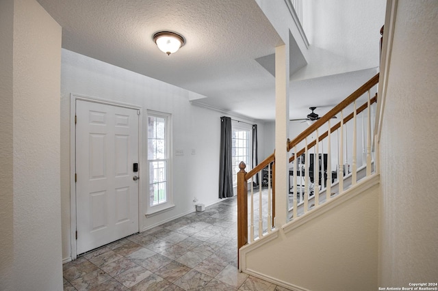 foyer featuring ceiling fan and a textured ceiling