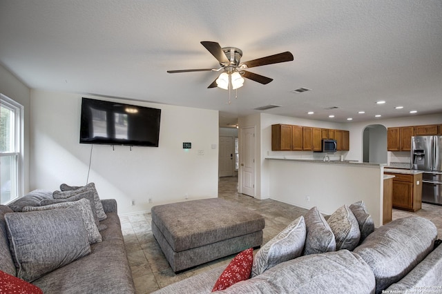 living room featuring ceiling fan and a textured ceiling