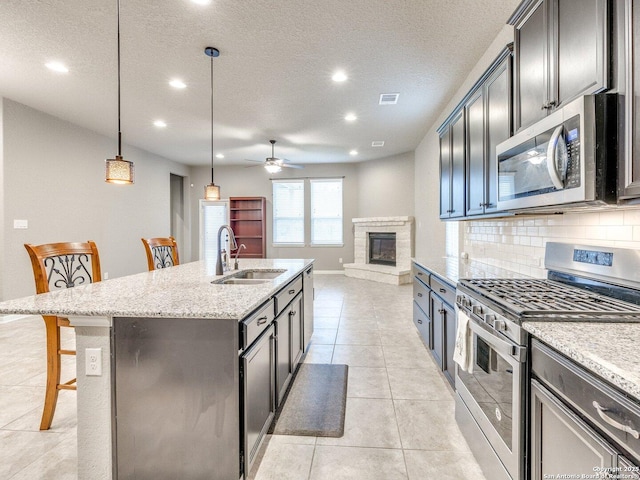 kitchen with sink, hanging light fixtures, a kitchen breakfast bar, a center island with sink, and appliances with stainless steel finishes