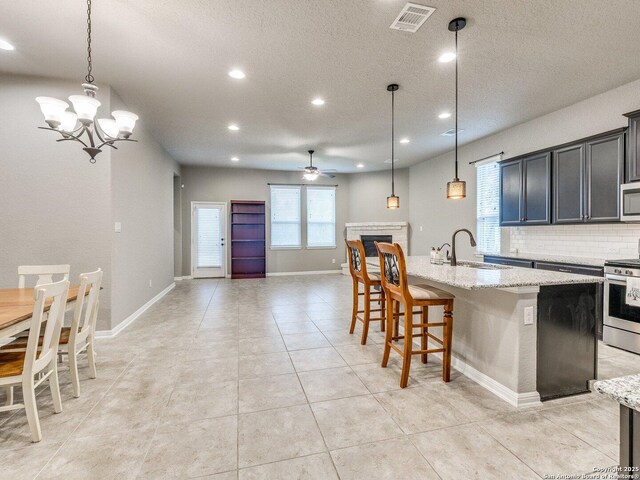 kitchen featuring a center island with sink, ceiling fan with notable chandelier, decorative light fixtures, and appliances with stainless steel finishes