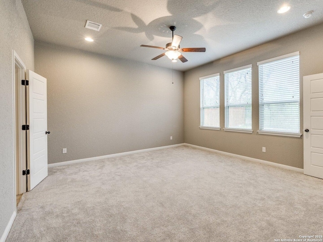 spare room featuring a textured ceiling, light colored carpet, and ceiling fan