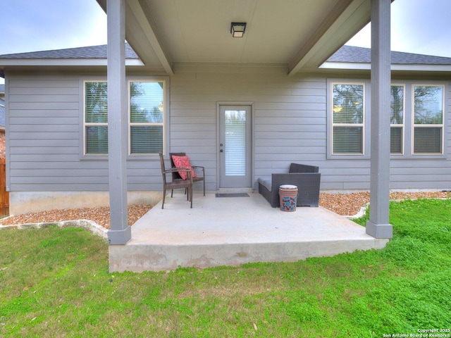 view of exterior entry with a lawn and a patio area