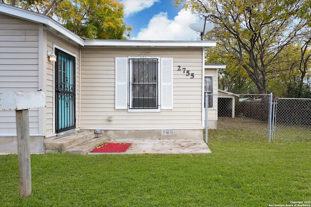 view of exterior entry featuring a lawn and a patio