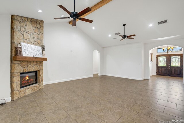 unfurnished living room featuring high vaulted ceiling, french doors, ceiling fan, a fireplace, and beam ceiling