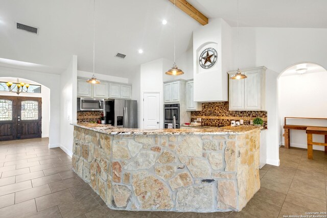 kitchen featuring appliances with stainless steel finishes, tasteful backsplash, beamed ceiling, decorative light fixtures, and light stone counters