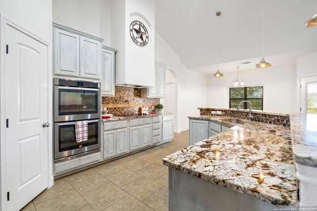 kitchen with backsplash, gray cabinetry, double oven, sink, and hanging light fixtures