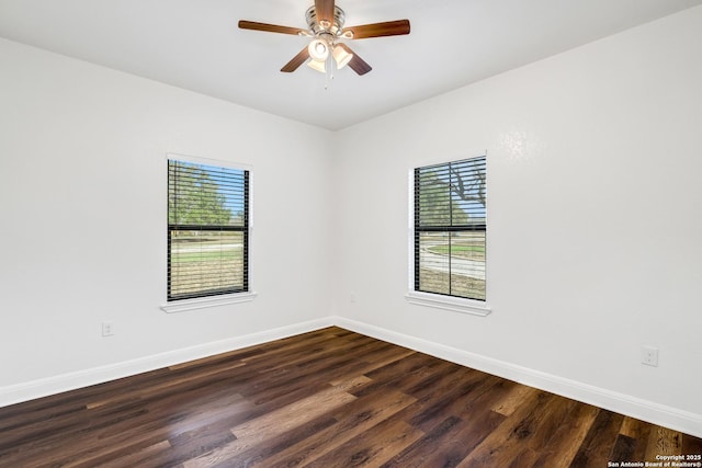 empty room with plenty of natural light, dark wood-type flooring, and ceiling fan