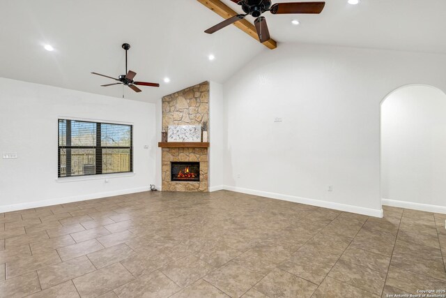 unfurnished living room with ceiling fan, beam ceiling, a fireplace, and high vaulted ceiling