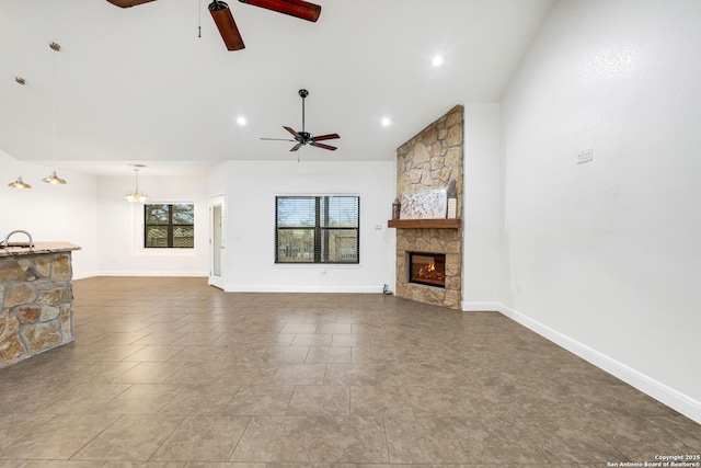 unfurnished living room featuring a fireplace, ceiling fan with notable chandelier, and sink