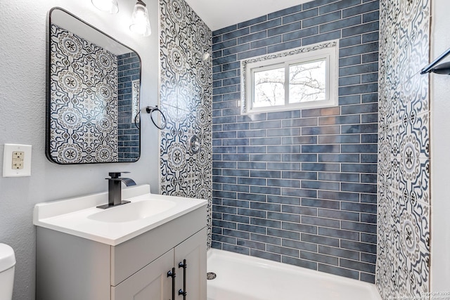 bathroom featuring a tile shower, vanity, and toilet