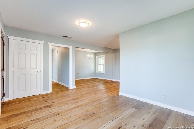 empty room with a chandelier and light hardwood / wood-style floors