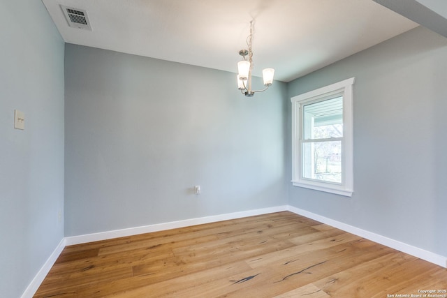 spare room with a chandelier and light hardwood / wood-style floors