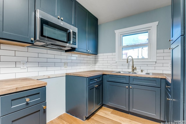 kitchen featuring wooden counters, light wood-type flooring, backsplash, and sink