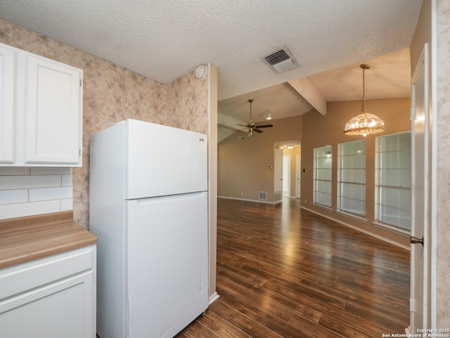 kitchen featuring ceiling fan with notable chandelier, white refrigerator, decorative light fixtures, white cabinets, and vaulted ceiling with beams