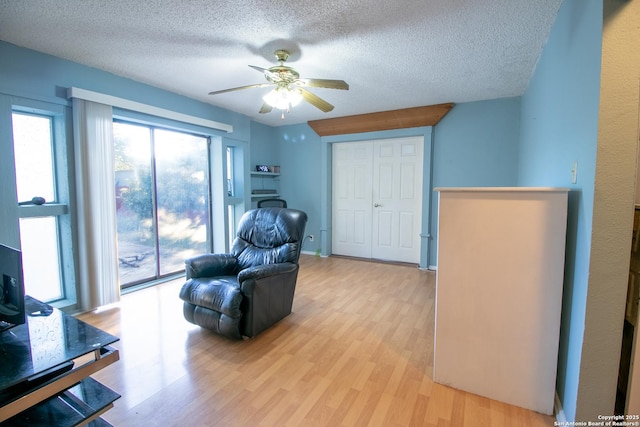 sitting room featuring ceiling fan, light hardwood / wood-style flooring, and a textured ceiling