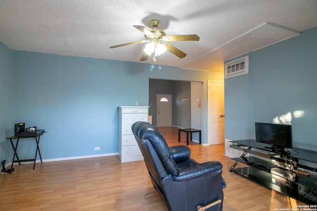 living room with ceiling fan, wood-type flooring, and a textured ceiling