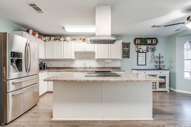 kitchen with island range hood, light hardwood / wood-style flooring, white cabinets, stainless steel fridge with ice dispenser, and a kitchen island