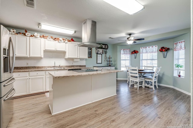 kitchen with a center island, light stone counters, stainless steel refrigerator with ice dispenser, island range hood, and white cabinets