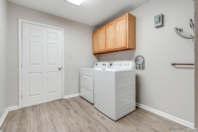 laundry area with washer and clothes dryer, cabinets, and light wood-type flooring