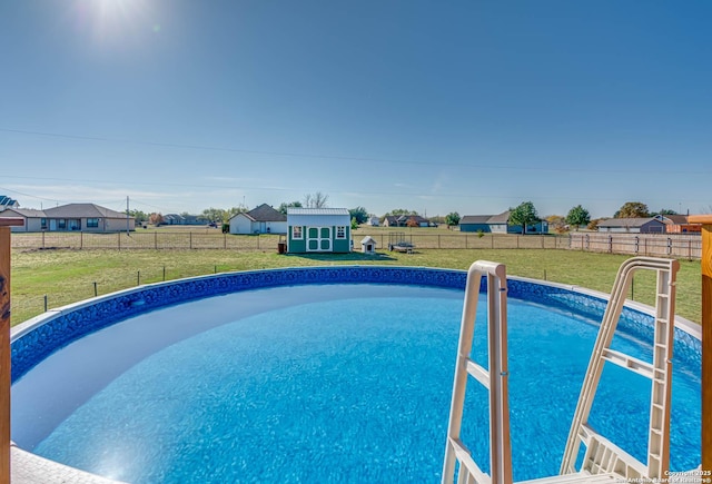 view of swimming pool with a shed and a yard