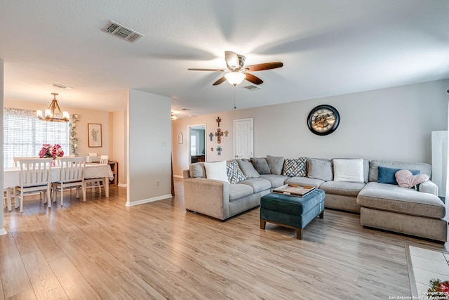 living room with light hardwood / wood-style floors and ceiling fan with notable chandelier