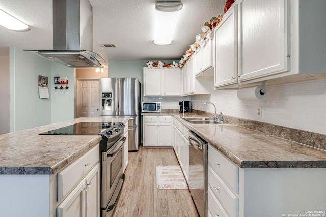 kitchen with white cabinets, appliances with stainless steel finishes, light wood-type flooring, and extractor fan