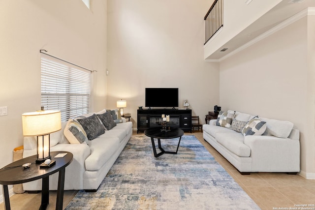 tiled living room featuring a towering ceiling, a healthy amount of sunlight, and ornamental molding