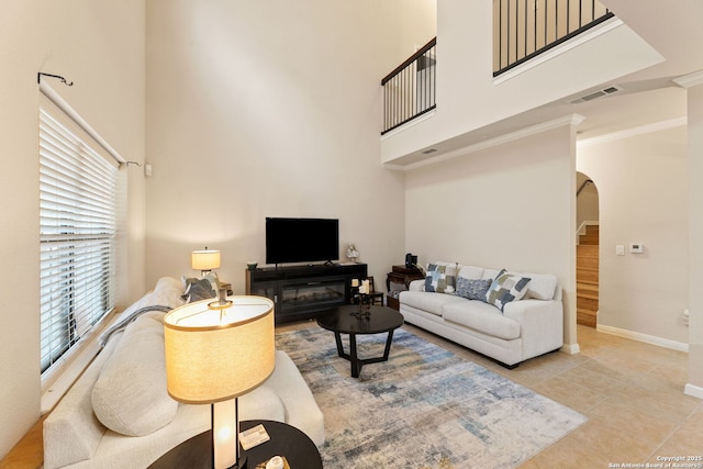 tiled living room featuring ornamental molding and a high ceiling