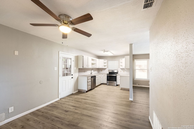 kitchen with sink, light hardwood / wood-style flooring, decorative backsplash, appliances with stainless steel finishes, and white cabinetry