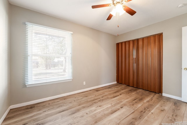 unfurnished bedroom featuring multiple windows, light wood-type flooring, a closet, and ceiling fan