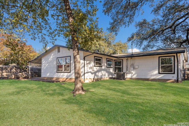 back of property with central air condition unit and a yard