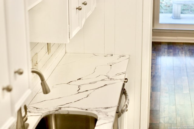 interior details featuring sink, light stone countertops, and white cabinets