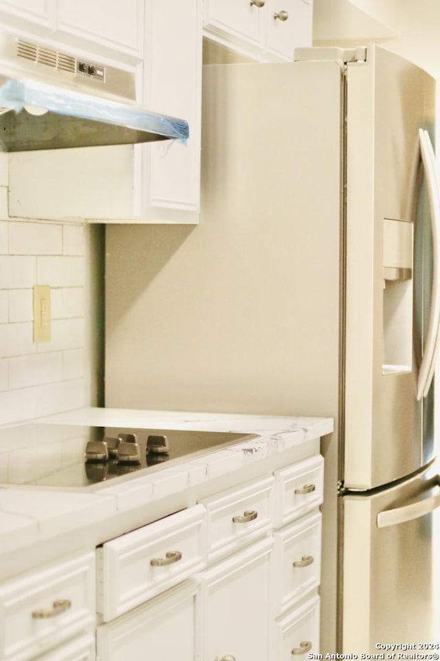 kitchen featuring light stone counters, decorative backsplash, and white cabinets