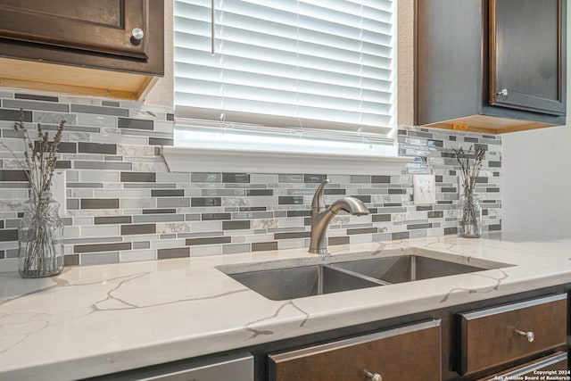 kitchen featuring light stone countertops, dark brown cabinetry, and backsplash