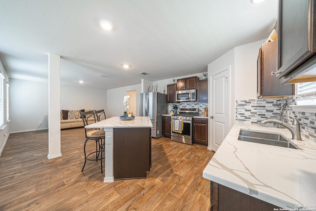 kitchen featuring a center island, sink, decorative backsplash, appliances with stainless steel finishes, and a kitchen bar