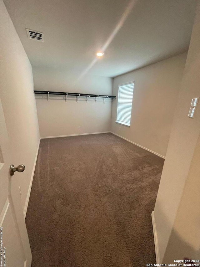 walk in closet with dark colored carpet