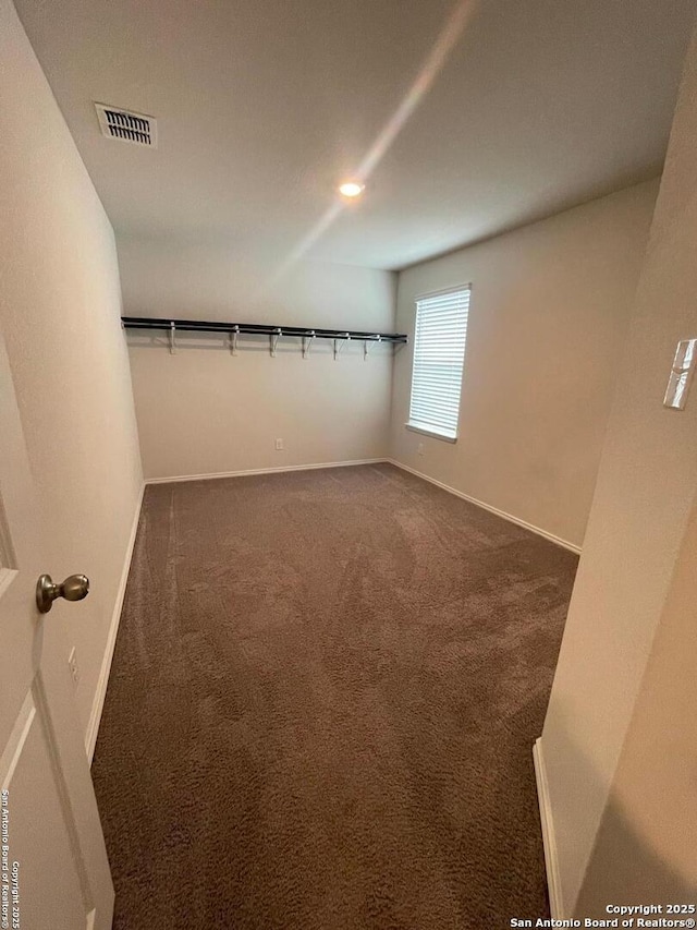 walk in closet with dark carpet