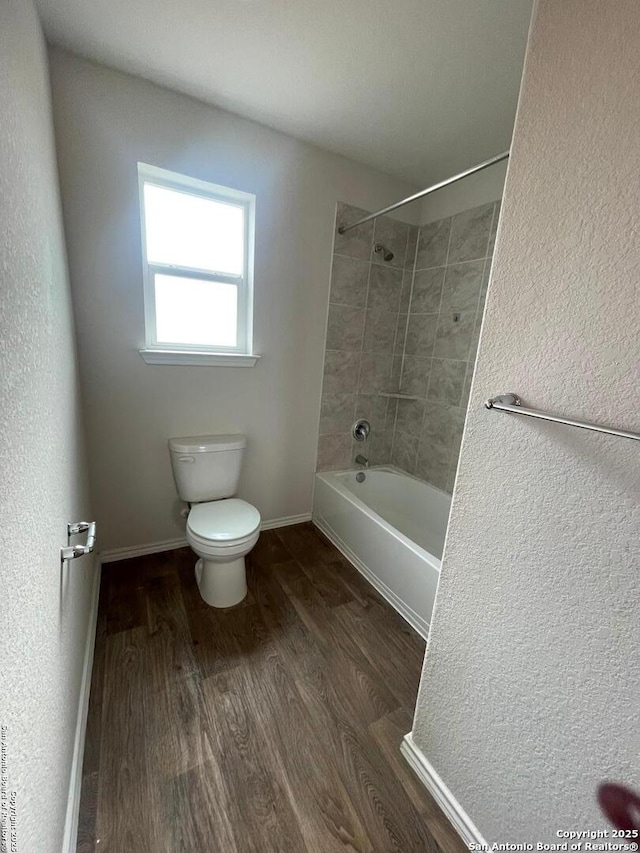 bathroom featuring toilet, tiled shower / bath, and hardwood / wood-style flooring