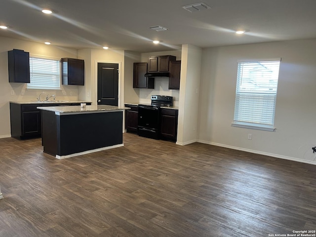 kitchen with light stone countertops, a center island, sink, dark wood-type flooring, and black electric range oven