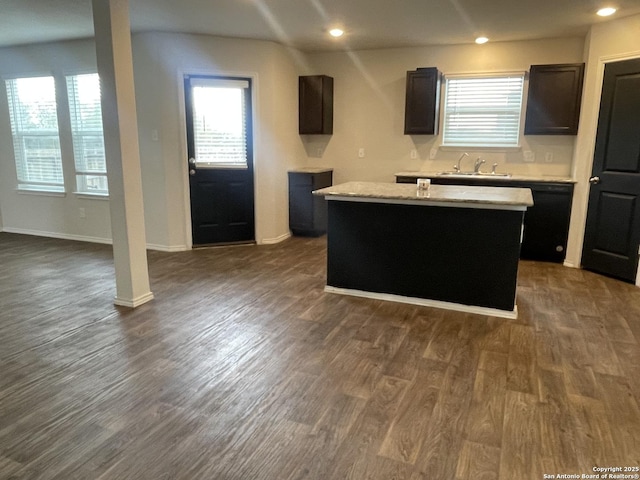 kitchen featuring dishwasher, sink, light stone counters, a kitchen island, and dark hardwood / wood-style flooring