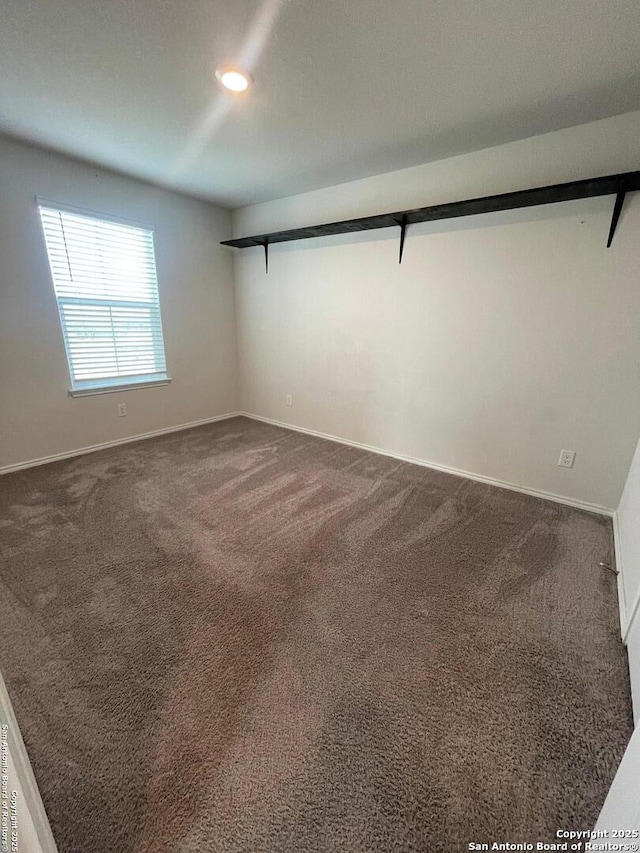 spare room with dark carpet